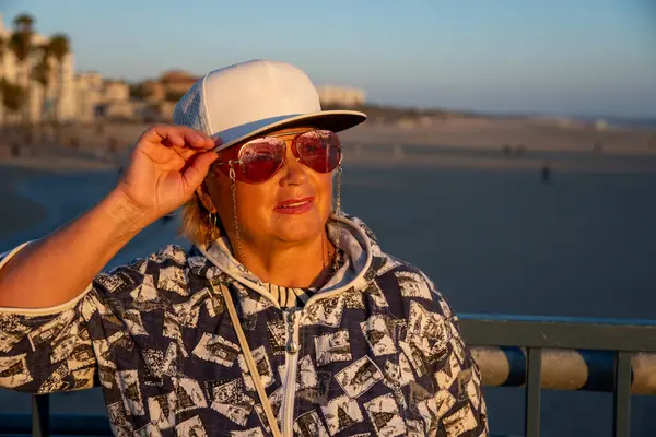 ロサンゼルスビーチでウォーキングを楽しむサングラスを持つシニア女性 — ストック写真