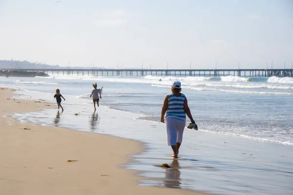 ロサンゼルスビーチでウォーキングを楽しむサングラスを持つシニア女性 — ストック写真