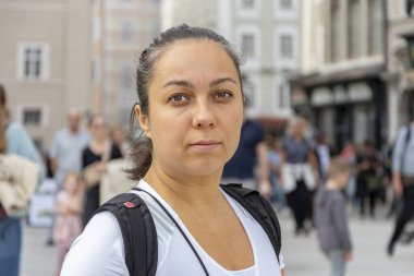 Eski şehir ve Avrupa mimarisinin bulanık arka planında sırt çantası olan beyaz tişörtlü bir kadın..