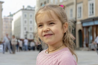 4-5 yaşlarında eski mimarinin bulanık şehir geçmişi olan küçük bir kız..