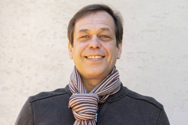 45-50 yaşlarındaki mutlu bir adamın portresi. Üzerinde hırka ve atkı var. Arka planda, yakın plan..