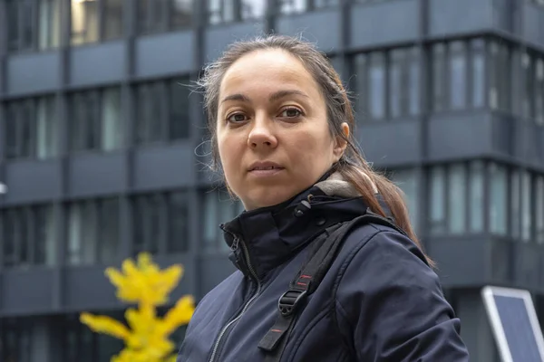 Stock image Street portrait of a woman 40-45 years old against a blurred background of modern buildings and yellow autumn leaves.