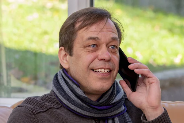 Äldre Leende Man Halsduk Som Pratar Smartphone Medan Han Sitter — Stockfoto