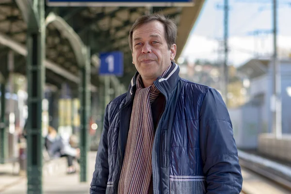 45-50 yaşlarındaki bir adamın sokak portresi Avrupa 'daki bir tren istasyonunda tren ya da banliyö trenini bekliyor..