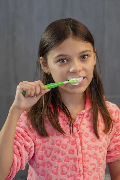 Portrét Krásné Dívky Čištění Zubů Růžovém Pyžamu Neutrálním Pozadí Koupelně — Stock fotografie