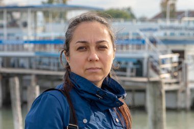 A beautiful 40-year-old woman with long hair on the background of a river marina. clipart