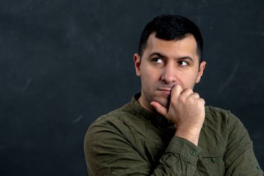 30-35 yaşlarındaki düşünceli bir adam siyah bir arkaplana bakar. Metnin için bir yer, kopyalama alanı..