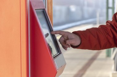 Bir adam elektronik bilet otomatından toplu taşıma için bilet alıyor..
