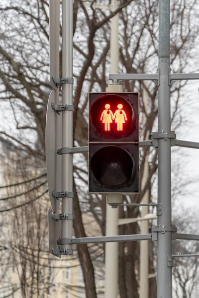 A red traffic light with the image of two female figures with hearts on a pedestrian crossing, prohibiting the signal light.