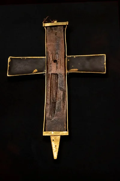 A piece of a wooden cross from the crucifixion of Christ on a black background, a Christian shrine, a Viennese treasury.