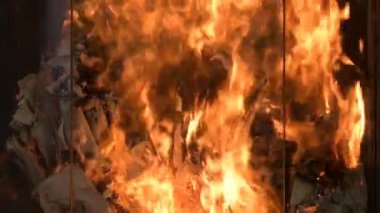 The flame of the fire in the fireplace burns paper or documents, close-up.