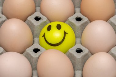 Tavuk yumurtalarının üzerinde gülen yüzlü bir top var. Kumaş bir arka plan..