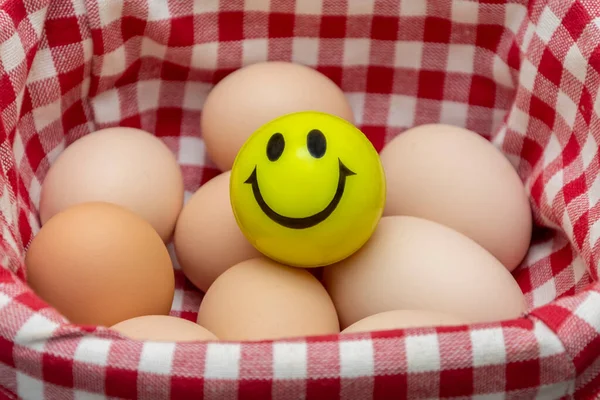 On the chicken eggs there is a ball with a smiley face, a textured fabric background.