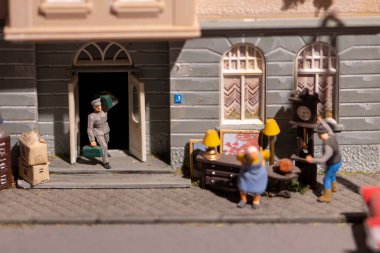Miniature scene of moving and settling people with old things into the house, toy models of people.