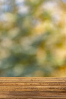 Textured wooden table with free space for your product or advertising text against a blurred background of a natural landscape, vertically.