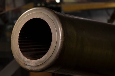 Muzzle of a large-caliber cannon with a rifled barrel from the Second World War, close-up.