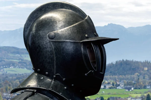 A knight in helmet and armor on the background of a natural mountain landscape.