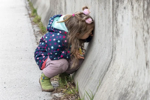 Mała Dziewczynka Zainteresowaniem Patrzy Przez Dziurę Betonowej Ścianie Koncepcja Ciekawość — Zdjęcie stockowe