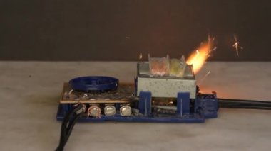 Elektrik panosundaki elektrik kabloları yanıyor ve ışıldıyor. Bükülmüş kablolarda kısa devre. Alevler, kıvılcım ve duman.