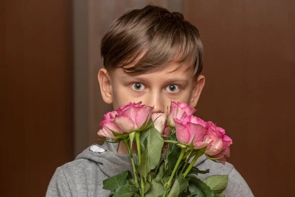 一个男孩 带着一束玫瑰 背景中性 头戴花冠 假期和祝贺 男性关注 — 图库照片