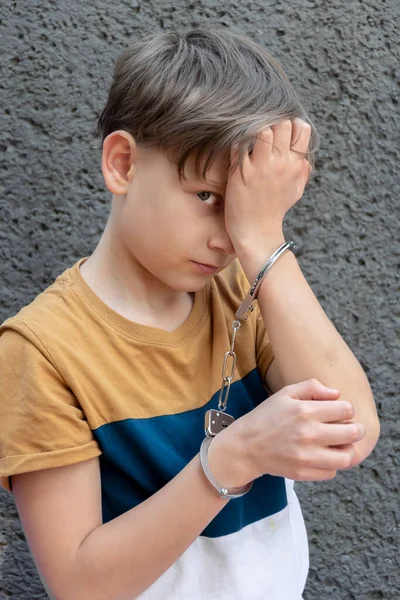 手錠をかけられた少年はカメラを見て感情的な肖像画少年非行少年 — ストック写真