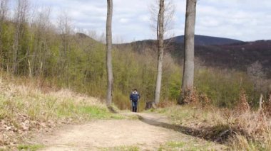 Bir adam engebeli arazide yürüyor, İskandinav yürüyüşü yapıyor..