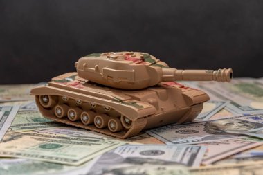 Dağınık Amerikan dolarları, siyah arka plan, yakın plan askeri tank. Konsept: silah harcamaları, askeri yardım, silah ve mühimmat ticareti, para kredisi, Ukrayna 'da savaş.