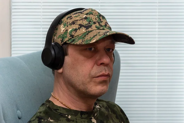 Mężczyzna Mundurze Wojskowym Noszący Słuchawki Siedzi Krześle Przy Oknie Koncepcja — Zdjęcie stockowe