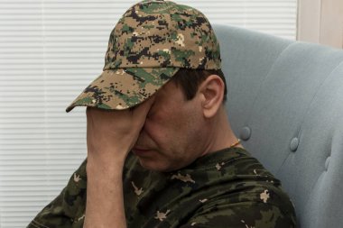 45-50 yaşlarında yaşlı bir asker sandalyeye otururken elleriyle yüzünü kapadı. Konsept: Askeri personelde zihinsel bozukluklar, bir psikoterapist tarafından tedavi.
