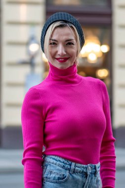 Sarışın bir kadın 35-40 yaşlarında, gece vitrinlerinin arka planında bulanık bir şapka takıyor, fenerlerin parıltısı....