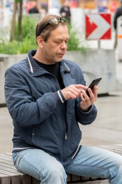 Şehirde yaşlı bir adam telefonla konuşuyor..