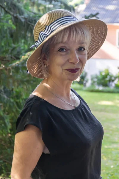 ヨーロッパのカントリーハウスの背景に わら帽子をかぶった60 65歳の高齢女性の肖像画 垂直写真 — ストック写真
