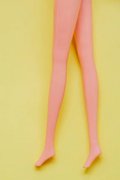 黄色背景的塑料细长娃娃腿 — 图库照片