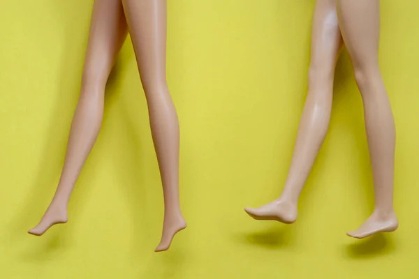 黄色背景上的一双塑料玩具腿 — 图库照片