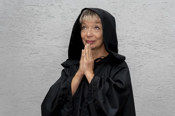 一个60岁至65岁的老年修女穿着黑色长袍在墙壁的浅色背景下的画像 前往圣地朝圣 — 图库照片