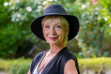 60-65 yaşlarındaki yaşlı kadın, siyah şapkalı, doğaya aykırı biri..