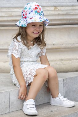  Eski bir Avrupa binasının mermer basamaklarında panamayla oturan 5 yaşında bir kız. Konsept: Turizm ve aile tatili, tarihi yerleri ziyaret.