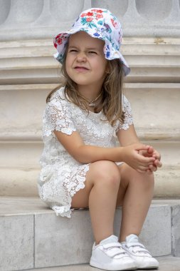  Eski bir Avrupa binasının mermer basamaklarında panamayla oturan 5 yaşında bir kız. Konsept: Turizm ve aile tatili, tarihi yerleri ziyaret.