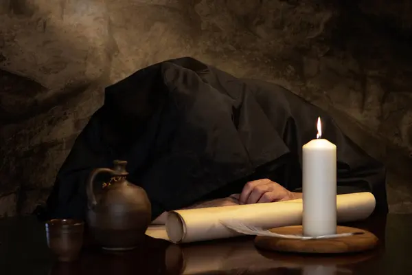 A monk in a black cassock fell asleep drunk at a table with a jug of wine in a medieval coaching inn. Concept: drunkenness and alcoholism.