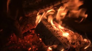 Şöminede yanan bir odun, yakın çekim, titreyen közler, ateş ve duman..