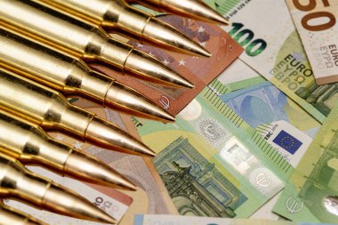 Sarı kartuşlar ve kovanlar Avro para banknotlarının üzerinde, yakın plan, seçici odaklanma. Kavram: Ukrayna 'da savaş, Avrupa' dan maddi destek, silah satışları ve yardım, orduda paralı asker işi, mühimmat ticareti.