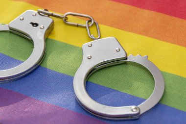 Polis kelepçeleri renkli bir LGBT bayrağına bağlı. Kavram: Rusya 'da suç işleme, yasaklama.