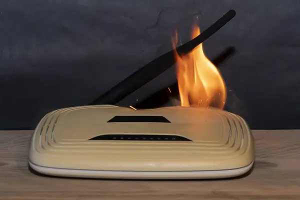 Wi-Fi router fires on a table in the house, smoke and fire.