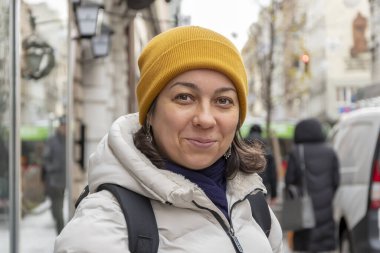 Şehrin arka planında, Avrupa kışında şapkalı gülümseyen bir kadının portresi..