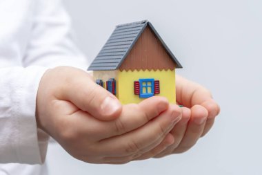 Çocuğun elinde küçük bir evin minyatür bir modeli var..