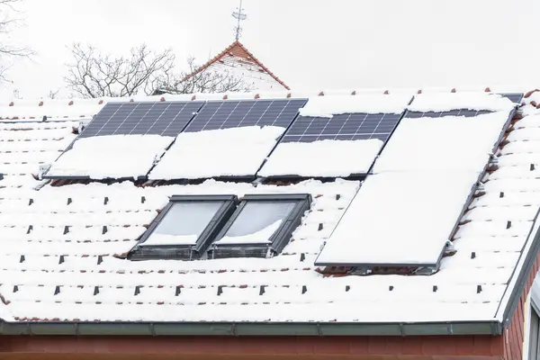 The roof of a solar panel house covered in snow.