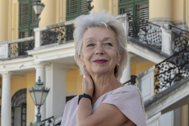 65-70 yaşlarındaki mutlu, gri saçlı bir kadının portresi Avrupa 'nın eski mimarisinin arka planına karşıydı..