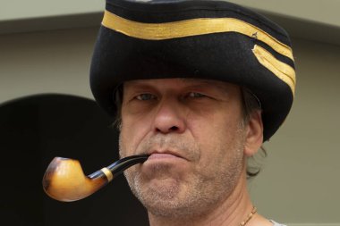 Ağzında piposu olan bir adam, keyfine bakıyor..