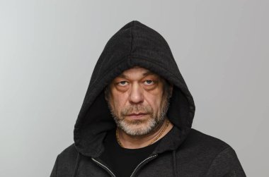 Açık arkaplanda kapüşonlu sweatshirt giyen vahşi yaşlı bir adamın duygusal portresi..