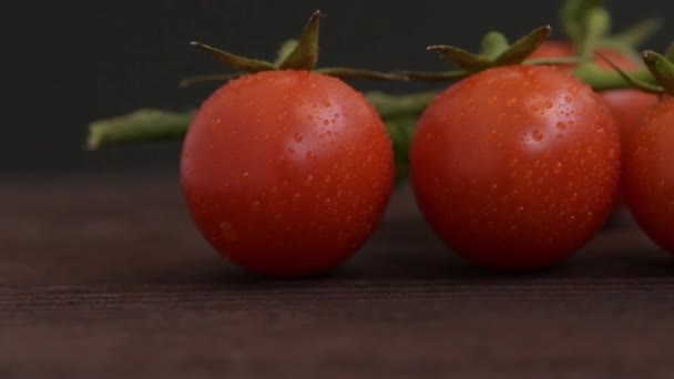 Cherry Rajčata Zelenými Prameny Dřevěném Povrchu Kapky Vody Zelenině Tmavé Stock Video